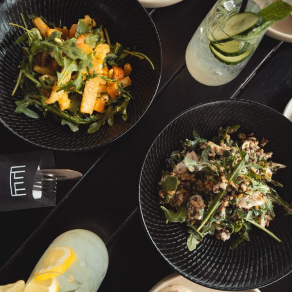 Top down image of 2 salads, surrounded by smaller tapas plates & drinks to promote Weekday Waterfront Lunch Specials at Edge Geelong